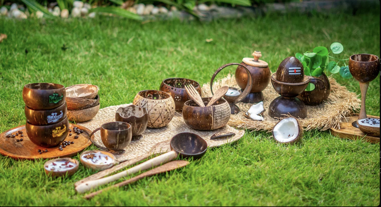 A spread of Natchu's coconut shell bowls, cups, spoons, and candle holders laid out on grass